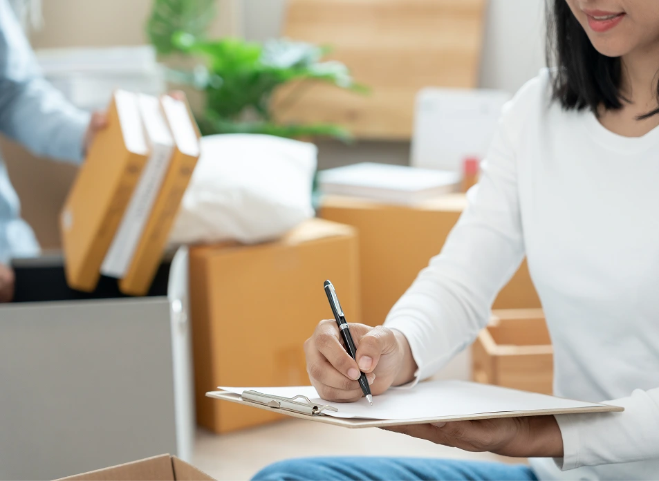 Woman writing on clipboard, organizing boxes